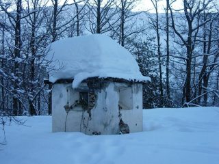 Un pilone votivo semisommerso dalla neve