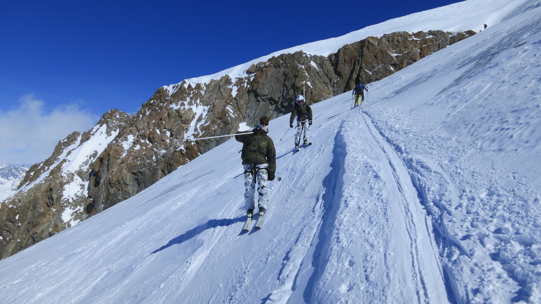 incrocio di Alpenjäger che scendono in un tratto con poca neve dura appoggiata sul ghiaccio