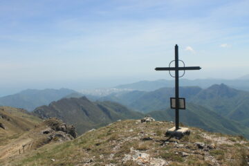 La croce di vetta; sullo sfondo la piana di Albenga.