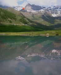 La parte alta dell'itinerario si specchia nell'acqua della diga (il punto rosso è il bivacco)