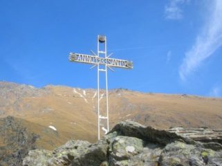 La croce presente sul roccione sopra il santuario. Sullo sfondo il Colle della Borra