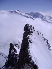 L'aerea cresta sommitale con gruppo del Rosa e nubi a fare da cornice