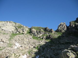 Sulla destra accanto al gendarme roccioso, la bocchetta della Perra. A sinistra oltre il bastione roccioso la striscia erbosa di salita