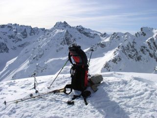 tripiede per autoscatto per la foto di vetta. Sullo sfondo le cime di Vens