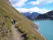 Sentiere lungo il lago con la diga sullo sfondo
