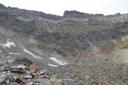 La testata del V.ne di Bioula vista dalla pietraia: al centro il terminale della pietraia nella zona dei nevai con, in rosso, il percorso seguito per portarsi sulla traccia a mezza costa