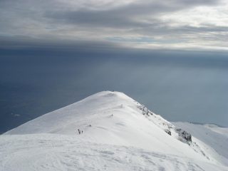 Dalla cresta che sovrasta la vetta, la vista del mare di nubi minacciose sulla pianura