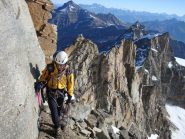 Un passaggio in cengia nell'ultimo terzo di cresta; alle spalle la magnifica bastionata di gneiss rosso sopra la quale si snoda la cresta percorsa.