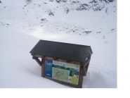 Dalla tettoia illustrativa. l'invaso vuoto del lago ricoperto di neve a grosse zolle