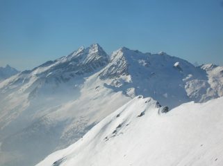 In ombra i pendii orientali del Voghel visti dai pressi della cima del Monte Cresto (Vallone di Tourrison). Al sole si intuisce il vallone che, dai piedi della cresta est, scende nel vallone di Scheity
