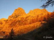 Montagne e larici rosso fuoco nella magica luce del tramonto