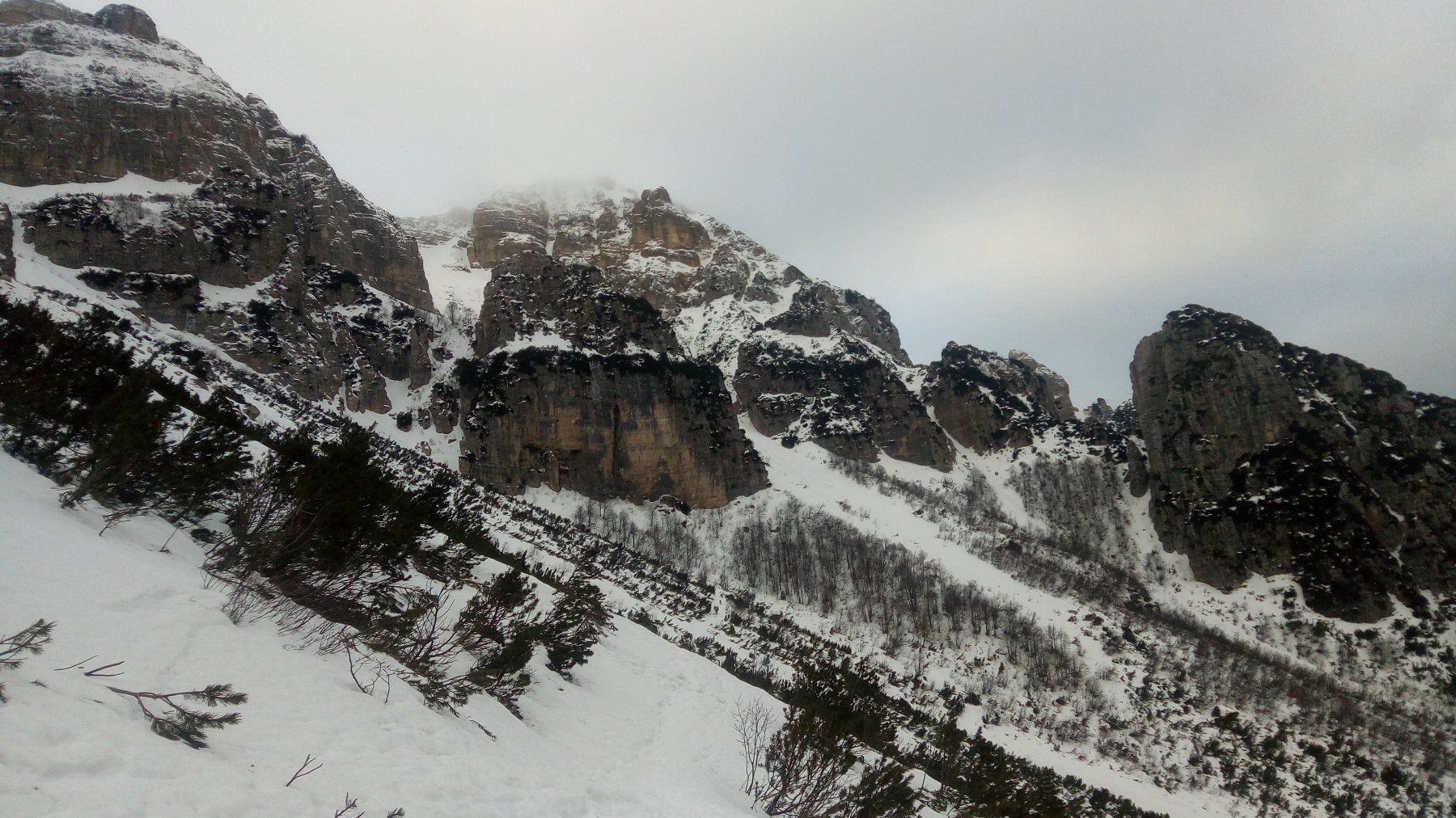 Al centro Cima Mosca avvolta nella nebbia, più in basso a destra fra le rocce il netto canale d'attacco