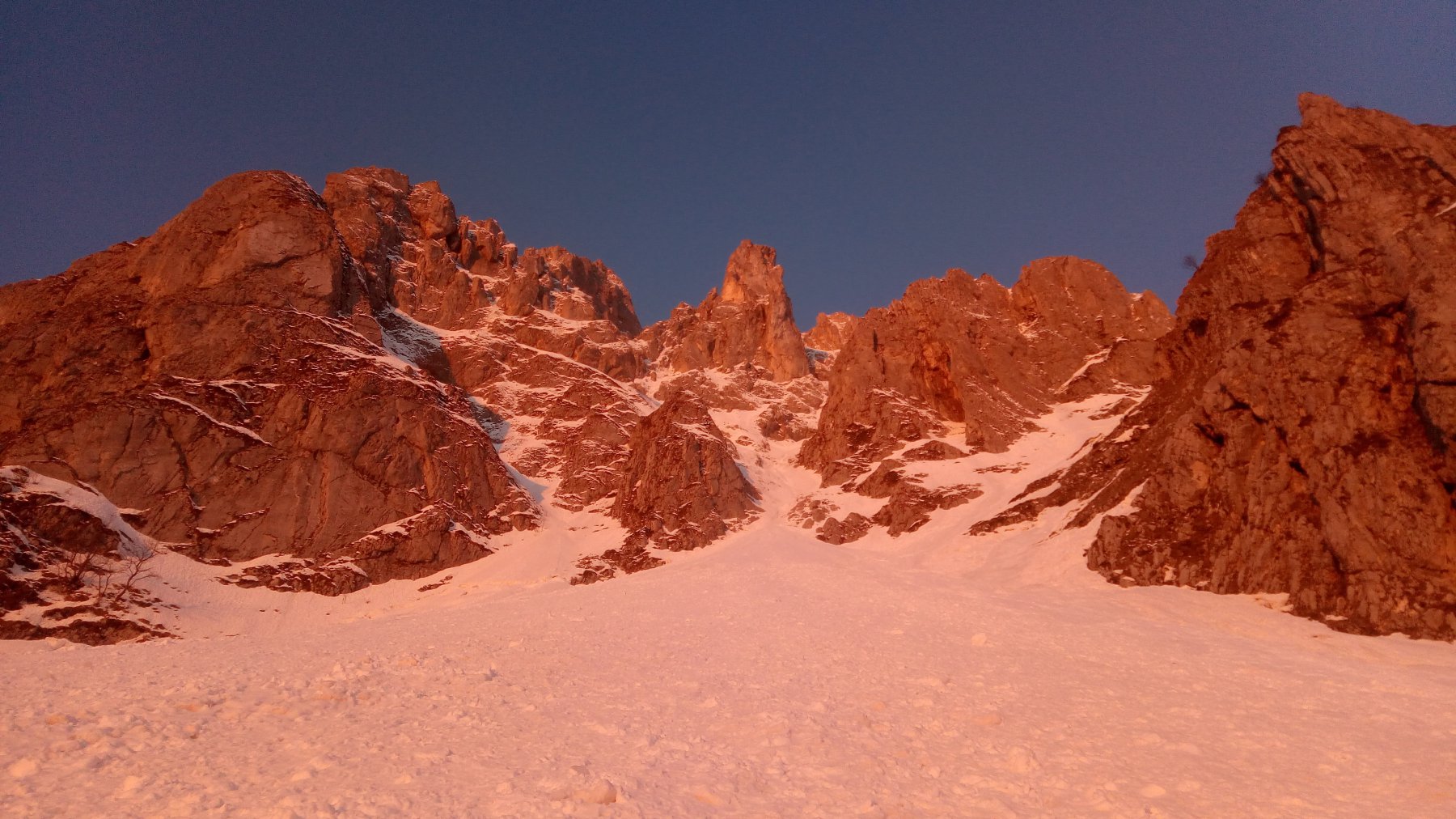 La parete rosseggia all'alba, al centro attacca la via