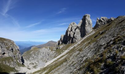 dal colletto Sud, bella vista sui torrioni del Cros. In fondo al vallone la sagoma del Monviso.