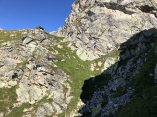 La traccia si inerpica sui prati appena sotto alla parete rocciosa