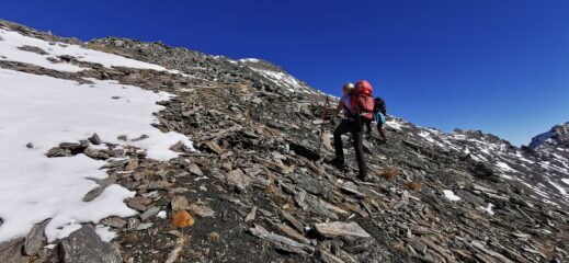 traversando il ripido pendio di pietrame che porta sul crestone SO del Roc del Boucher