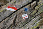 Passato il pianoro col Lago Rosso appaiono i bolli blu, qui con le tacche bianco-rosse-gialle e un’indicazione per la ferrata
