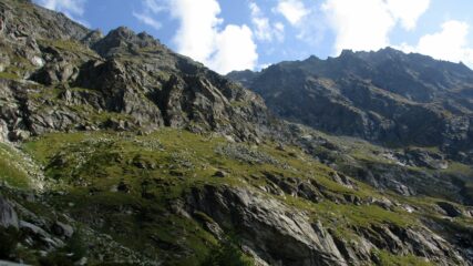 In direzione della bocchetta. Il sentiero attraversa i pratoni (un po' scoscesi) sotto la bastionata da sx a dx.