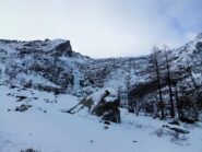 Al piano del Trione. Al centro la cascata ghiacciata. L'itinerario risale il pendio nevoso di sx, molto vicino alla bastionata, per poi curvare a dx sopra di essa, in costa.