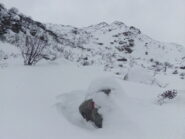 Il Gias di Mezzo spunta dalla neve (in centro), ormai sopra la bastionata. Dietro quest'alpe si vedono gli ultimi pendii di salita (poggiando a sx) e, contro il cielo, si indovina il tozzo ometto sul ciglio del piano dei laghi. 