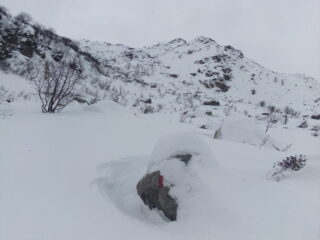Il Gias di Mezzo spunta dalla neve (in centro), ormai sopra la bastionata. Dietro quest'alpe si vedono gli ultimi pendii di salita (poggiando a sx) e, contro il cielo, si indovina il tozzo ometto sul ciglio del piano dei laghi. 