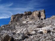 Il torrione sommitale visto dalla pietraia. La salita avviene nel primo canale da destra.