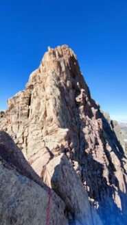 La cima occidentale vista dall'Oriente. Il penultimo tiro parte dall'intaglio tra le due cime, passa sulla cengia sulla parete nord e termina al di sotto di un masso con fenditura centrale già visibile in questa foto