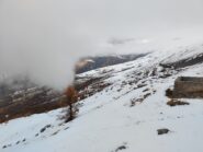 Dalla cima, quasi sull'orlo del pendio bianco sul fondo, al confine della zona innevata si scorgono le grange di Pian delle Stelle, sul punto di essere coperte dalla nuvola.