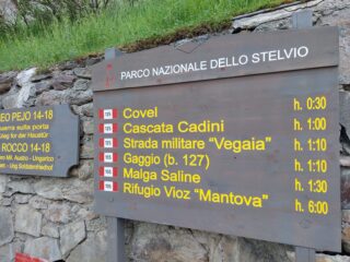 Tabella sentieri in prossimità della chiesa di Peio.