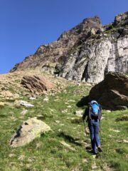 Marco in avvicinamento ai Piani della Rossa in direzione della pietraia che porta ad una cengia erbosa da traversare a destra per guadagnare il colle vicino all'attacco.