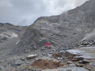L'ultima parte dell'itinerario.  Il circolino rosso indica l'attacco del secondo tratto attrezzato. In alto contro il cielo, quasi sull'orlo del tratto di cresta orizzontale, ingrandendo la foto si scorge la palina che segna la posizione del 