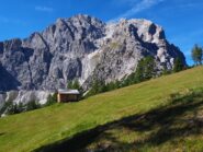 Poco sotto la cima un baitello con la Torre di sesto sullo sfondo.