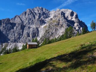 Poco sotto la cima un baitello con la Torre di sesto sullo sfondo.