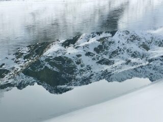 Riflessi su una porzione del lago blu non ancora ghiacciata