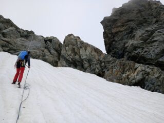 Calata su chiodo e spuntone uniti da cordino giallo e rosso, da accesso al nevaio/ghiacciaio e poi con una discesa faccia a monte si arriva alla pietraia e di lì alla normale.