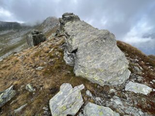 Sulla cresta, roccione con resti della segnaletica. il sentiero più evidente, scende a sinistra al colletto per innestarsi sulla via normale. Aggirare il roccione a destra e proseguire dritti sulla cresta...