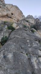 Placca grigia con cordone da cui attacca la via. Si intravedono anche lo strapiombino di L2 e il camino di L3.