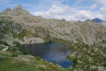 Il Lago Vercoche salendo al Col Laris, con il ricovero e lo sbarramento sull'emissario, che va attraversato per imboccare il sentiero