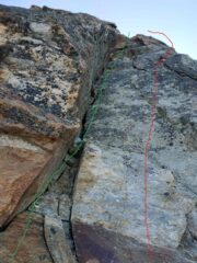 Passo chiave della via con 2 possibilità. Alpinista con scarponi: in verde, diedro + tetto. Falesista con scarpette: in rosso, placca + spigolo. 